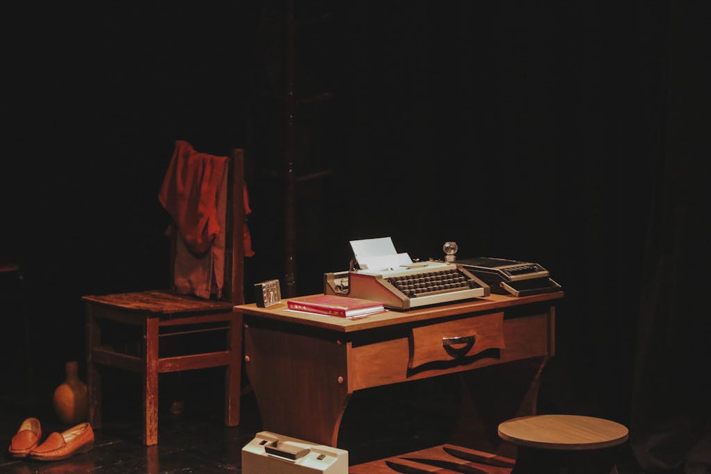 A nostalgic setup featuring a vintage office desk with a typewriter on a dimly lit theater stage.